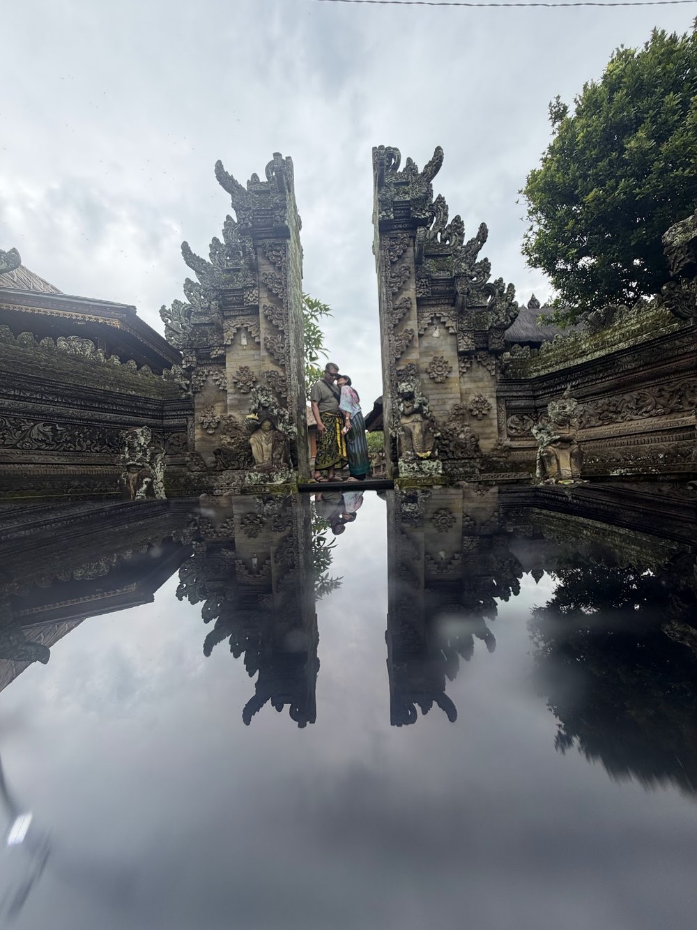 Guests at a Balinese split-gate temple with a mirror reflection