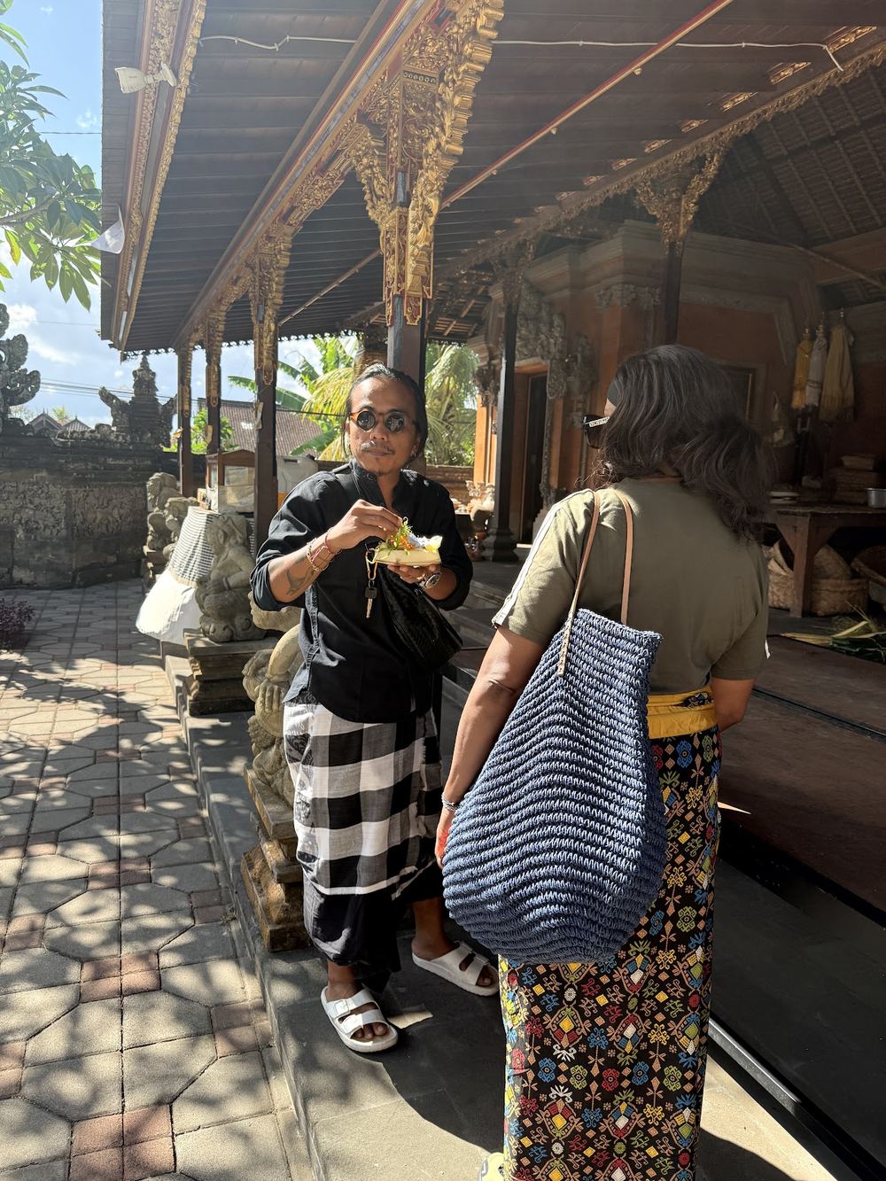 Awan preparing a temple offering with a guest at a Balinese temple